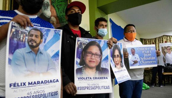 Nicaragüenses en el exilio sostienen carteles con las imágenes y nombres de presos políticos bajo el régimen de Daniel Ortega. / EZEQUIEL BECERRA / AFP