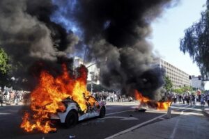 Aspecto de dos taxis ardiendo, después de los enfrentamientos entre manifestantes y agentes policiacos en las inmediaciones del Centro de Detenciones de Los Angeles. Crédito: AP