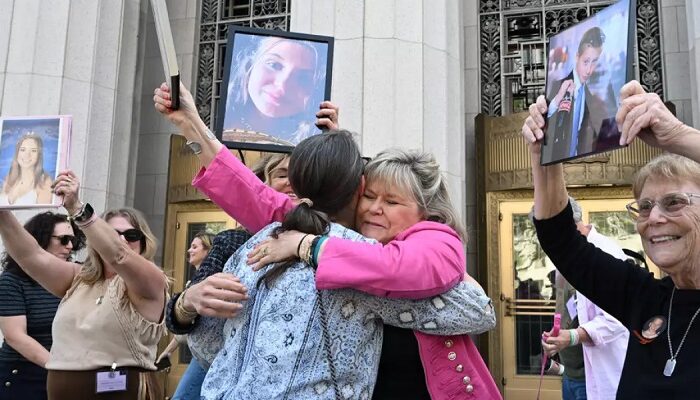 Lori Schott, centro, sostiene una foto de su hija Annalee Schott, tras el veredicto en un trascendental juicio sobre si las redes sociales vuelven adictos y perjudican deliberadamente a los menores en el Tribunal Superior de Los Ángeles, el miércoles 25 de marzo de 2026, en Los Ángeles. (William Liang / Associated Press)