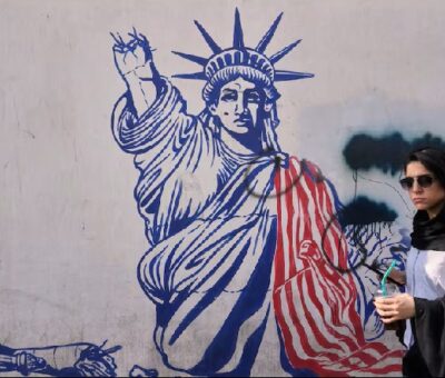 Una mujer pasa ante un mural en la pared de la antigua embajada de Estados Unidos en Teherán, ahora convertida en un museo. Foto: AP 