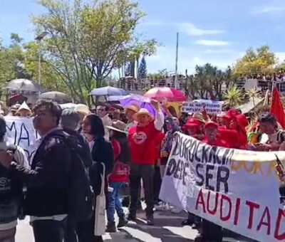 Dos personas cargan una pancarta blanca que dice "El maestro luchando también están enseñando" en un parque. La protesta en la BUAP. (Especial)