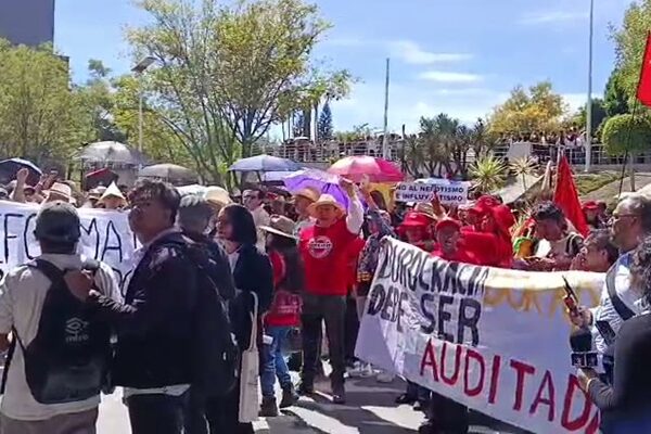 Dos personas cargan una pancarta blanca que dice "El maestro luchando también están enseñando" en un parque. La protesta en la BUAP. (Especial)